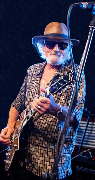 Older man playing guitar on stage.