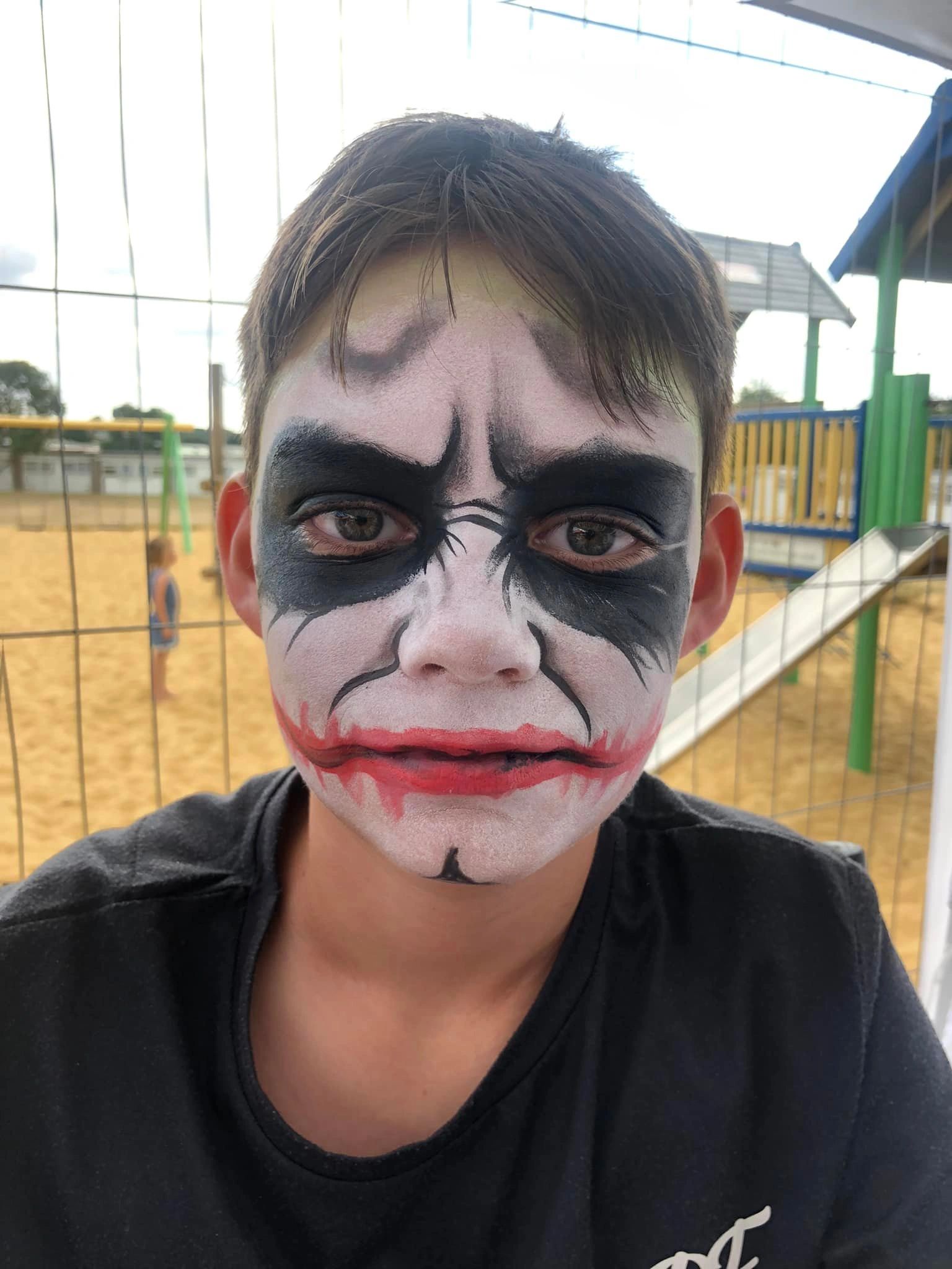 Boy with Joker-inspired face paint at a playground.