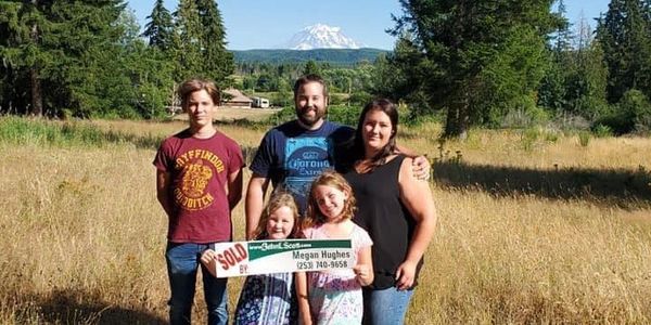 Family of 5, Dad, Mom, and 3 children smiling and holding a sold sign.