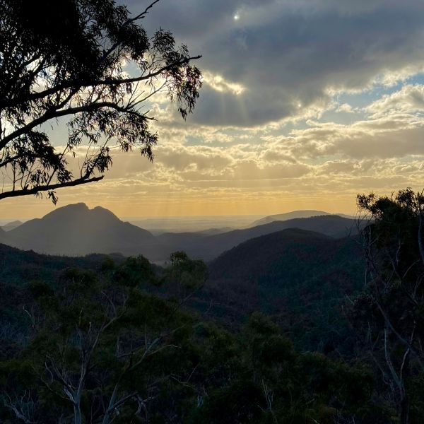 Sunset over misty mountains with scattered clouds.