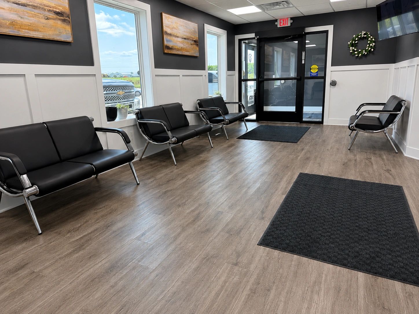 Modern waiting room with black chairs and large windows.