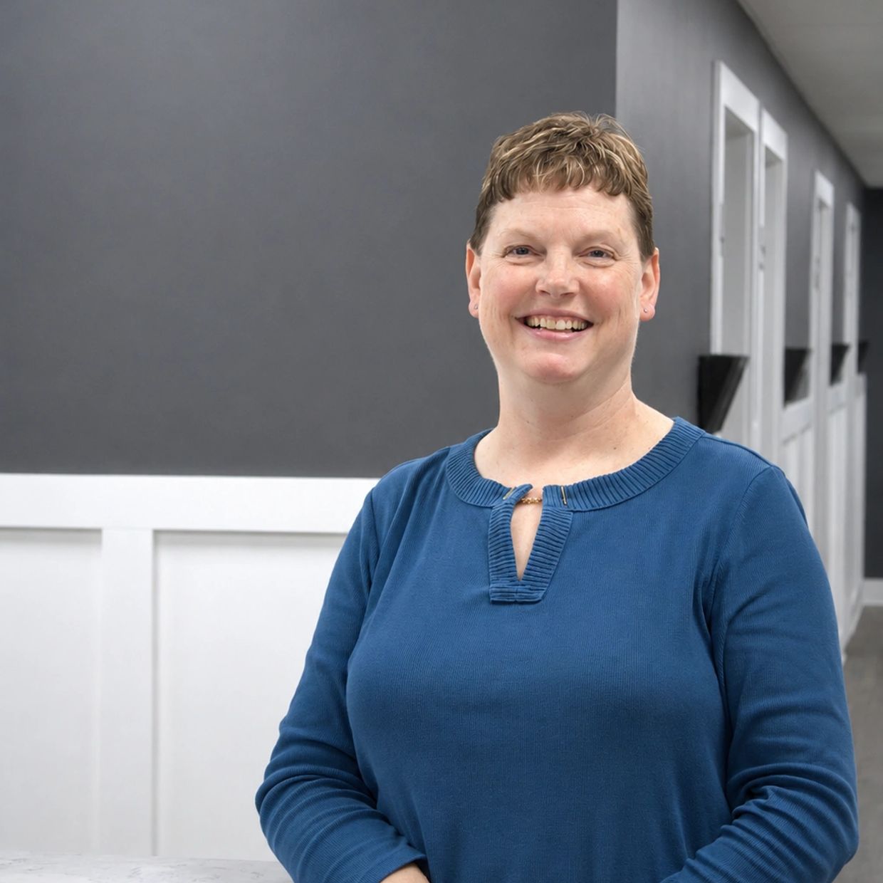 Smiling woman in blue sweater indoors.