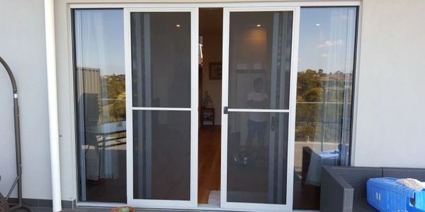 Sliding glass door with mesh screens leading to an indoor living space.