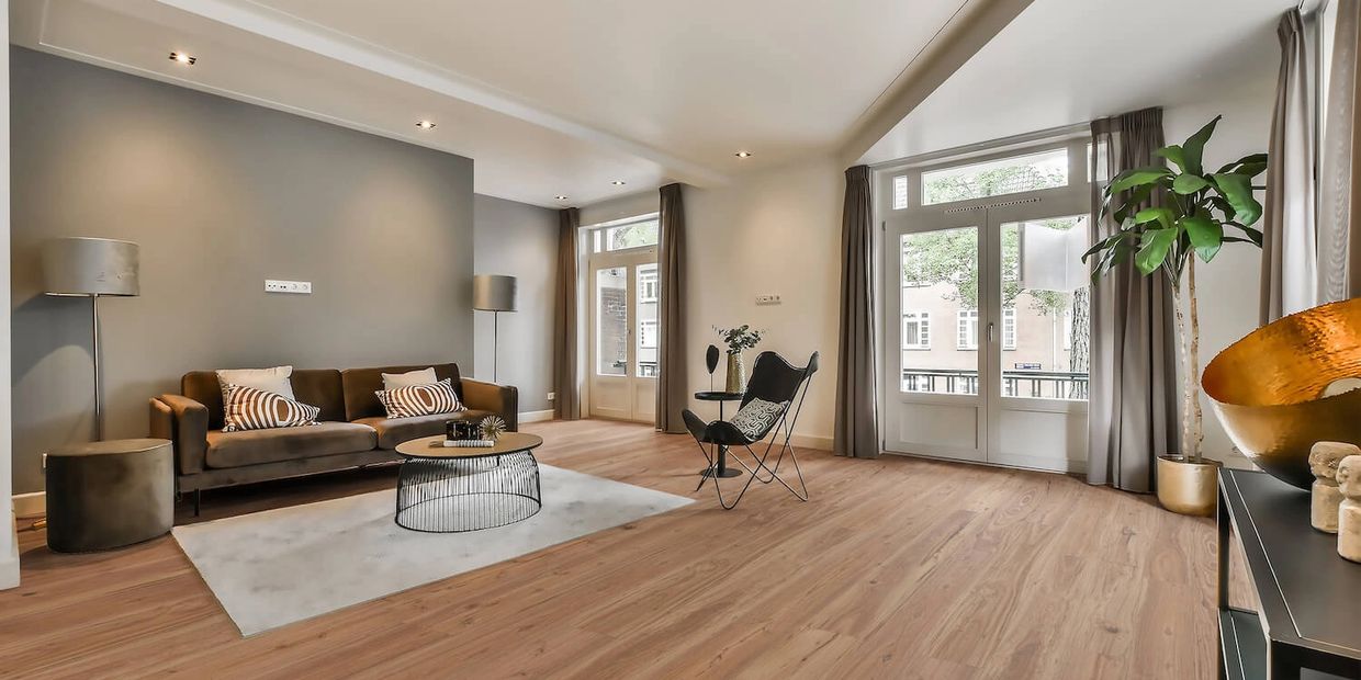 Modern living room with brown sofa, black chair, and large windows.