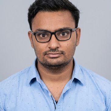 Portrait of a man wearing glasses and a light blue shirt.