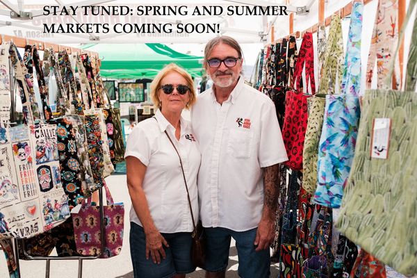 Couple stands in a colorful market selling bags and accessories.