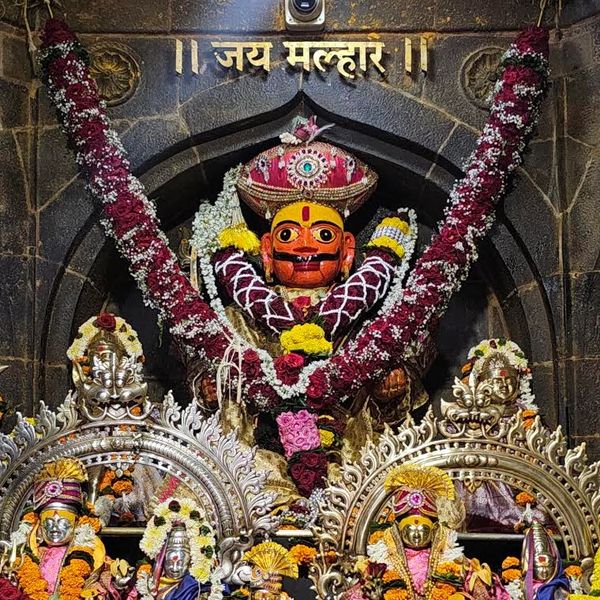 Colorful deity statue adorned with flowers inside a temple.