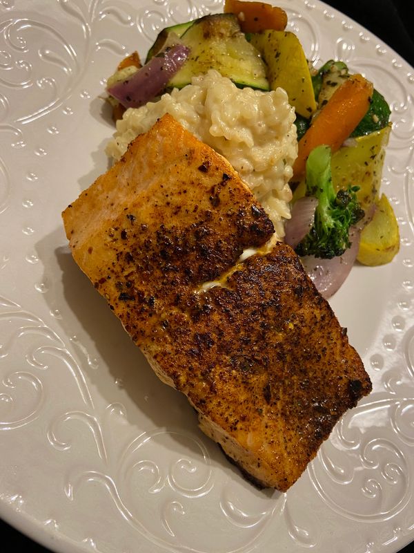 Pan seared salmon with Parmesan risotto and sautés vegetables on a plate