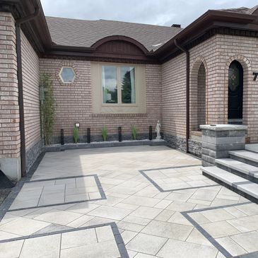 Modern brick house entrance with patterned stone driveway and steps.