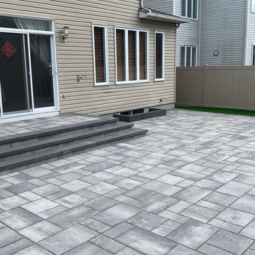 Modern backyard patio with gray stone pavers and steps.