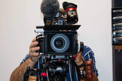 Person filming with a professional video camera indoors.