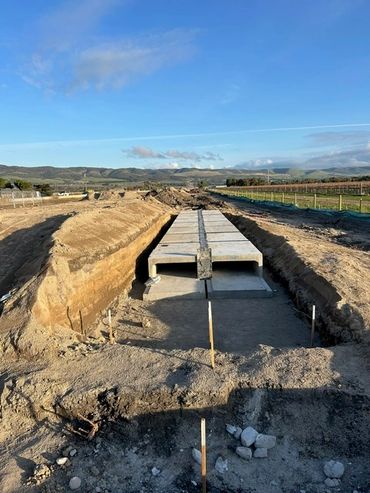 A newly constructed concrete drainage channel under clear skies.