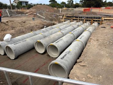 Concrete pipes laid out at a construction site for installation.