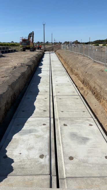 Construction site with concrete channel installation under clear blue sky.