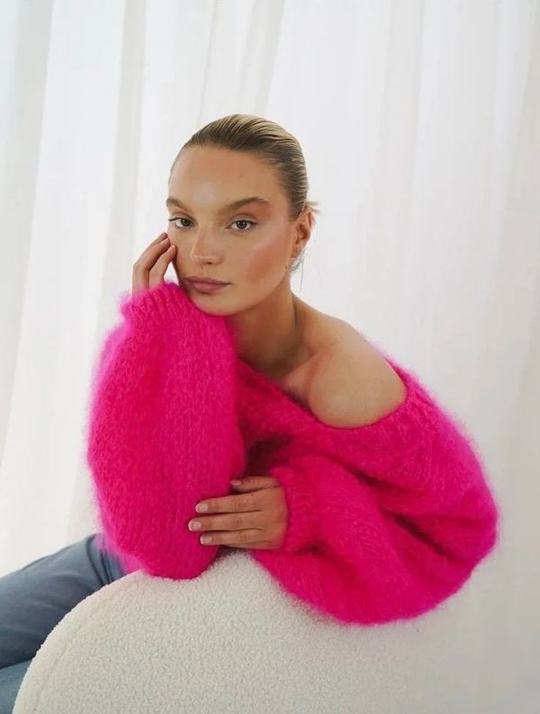 Woman in a bright pink fuzzy sweater posing thoughtfully.