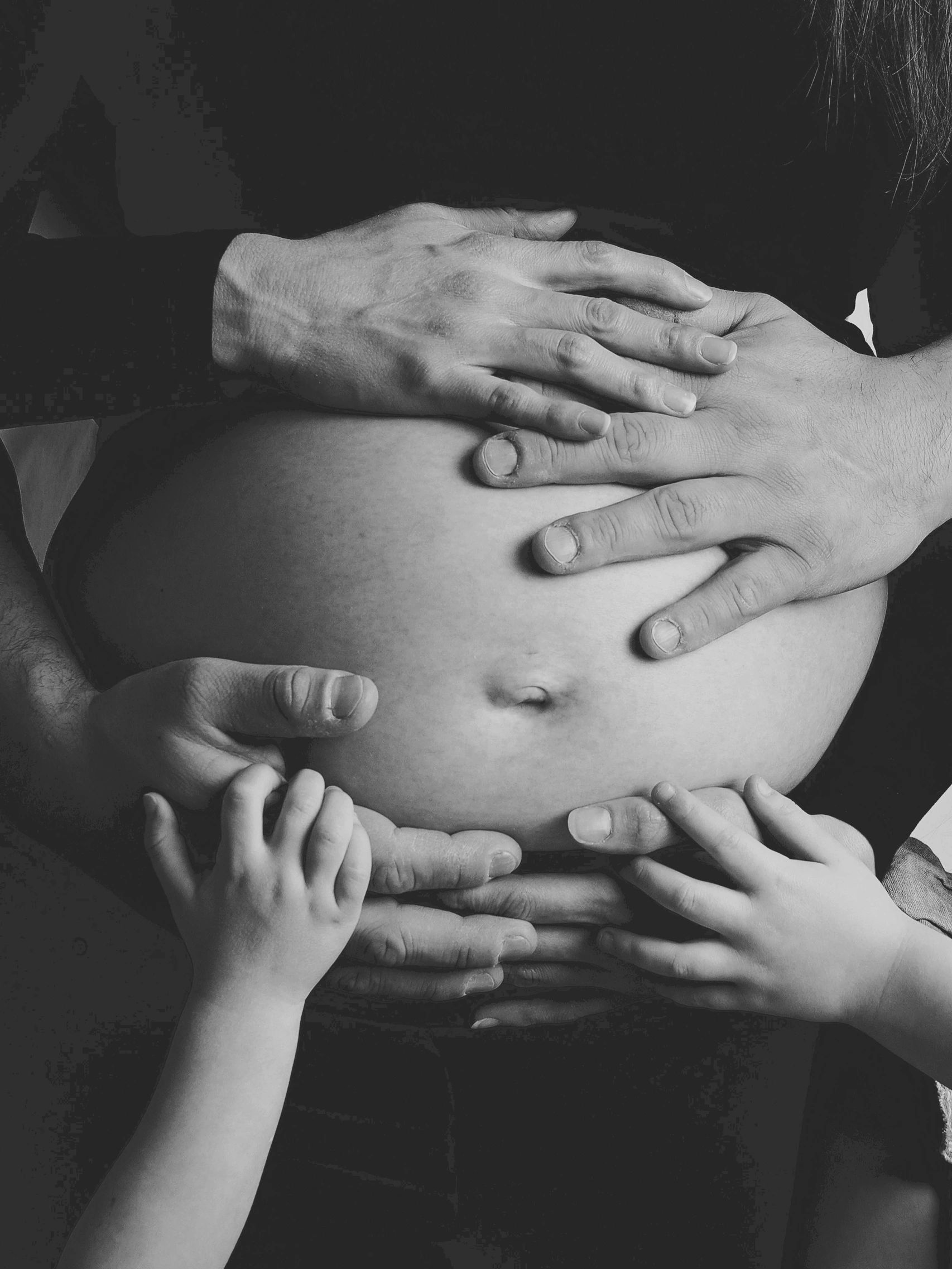 Hands gently touching a pregnant belly.