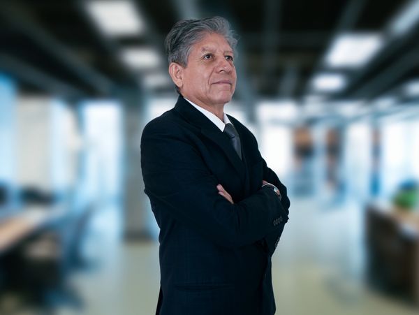 Hombre mayor en traje formal en una oficina.