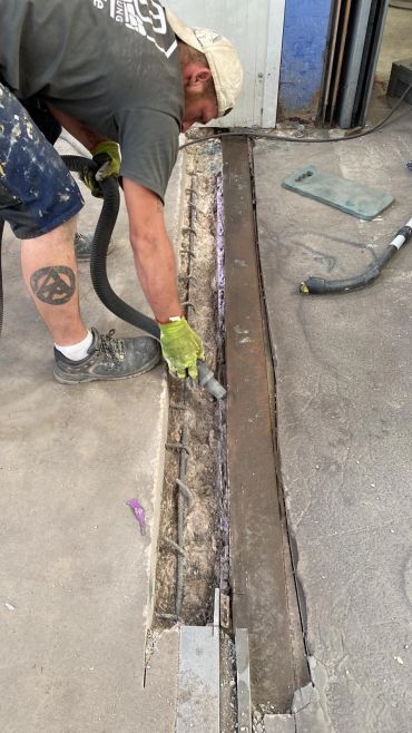 Handwerker reinigt einen Betonspalt mit einem Staubsauger.
