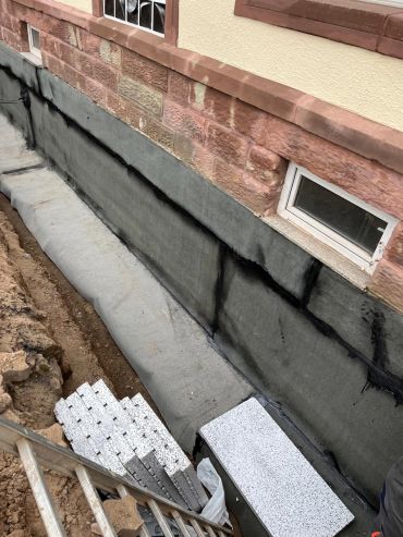 Hausmauer mit neuer Abdichtung im Kellerbereich.