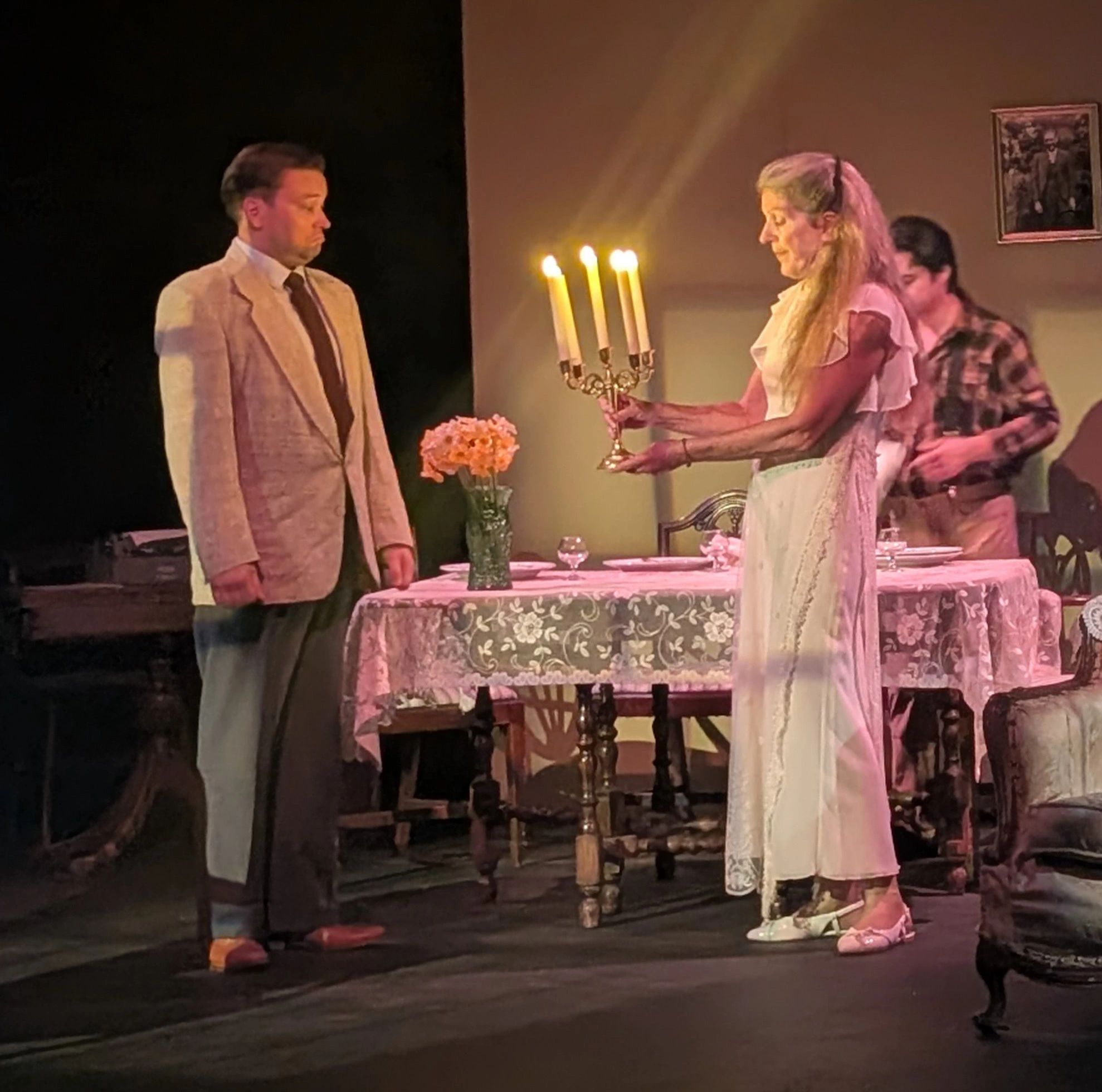 Woman holding a candelabrum towards a man at a dining table.