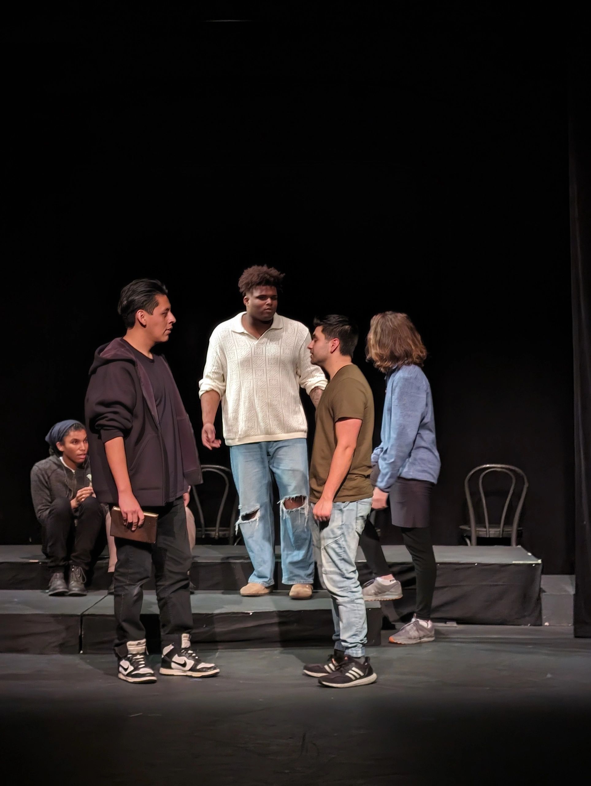 Group of young people on stage in a dramatic scene.