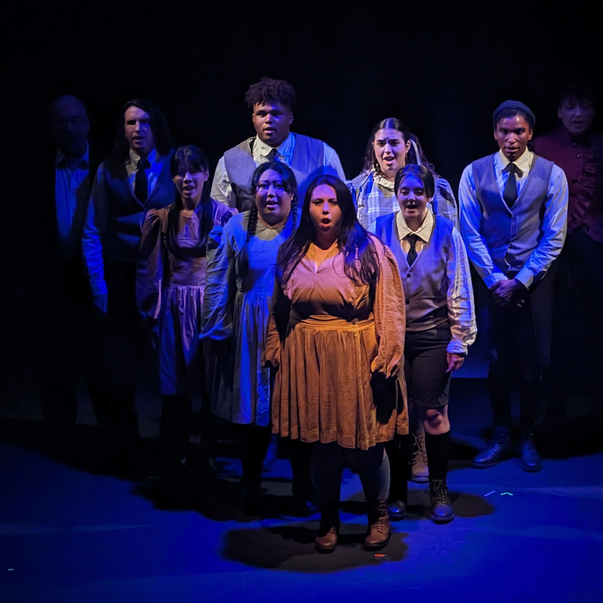 Theatre performers on stage during a dramatic scene.