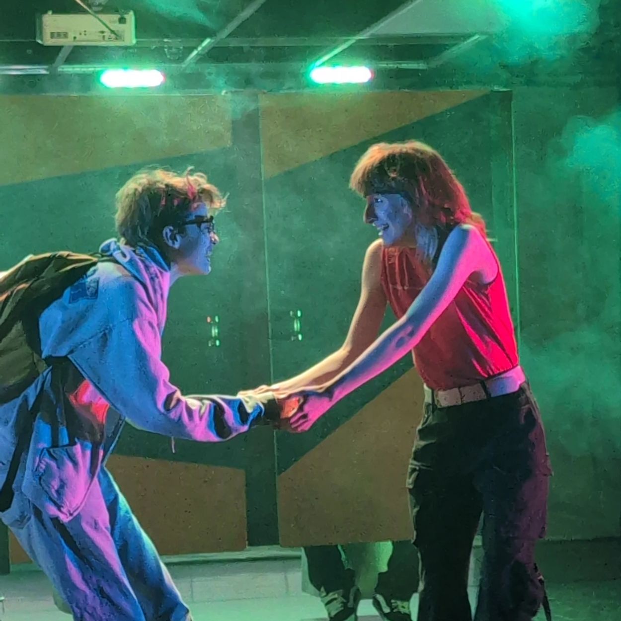Couple dancing under colorful lights in a foggy room.