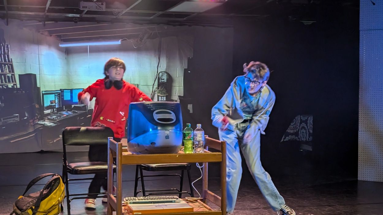 Two people in a room with an old Apple computer and drinks.