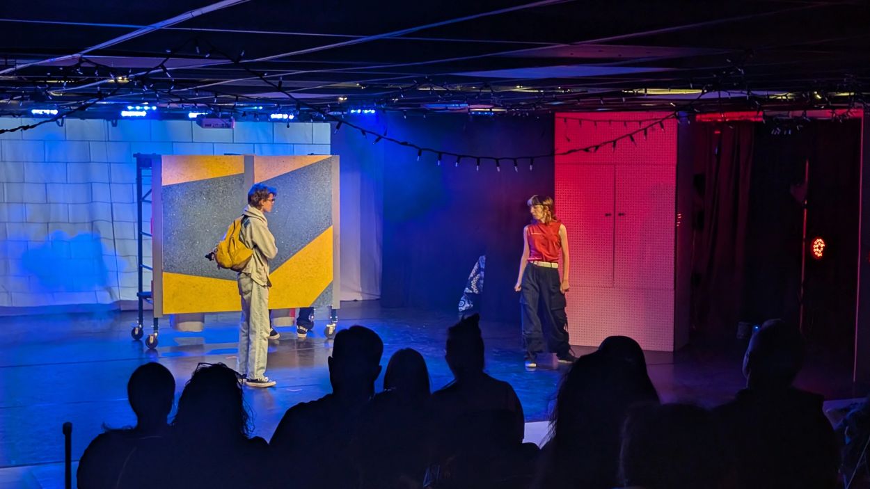 Two performers acting on stage in front of an audience.