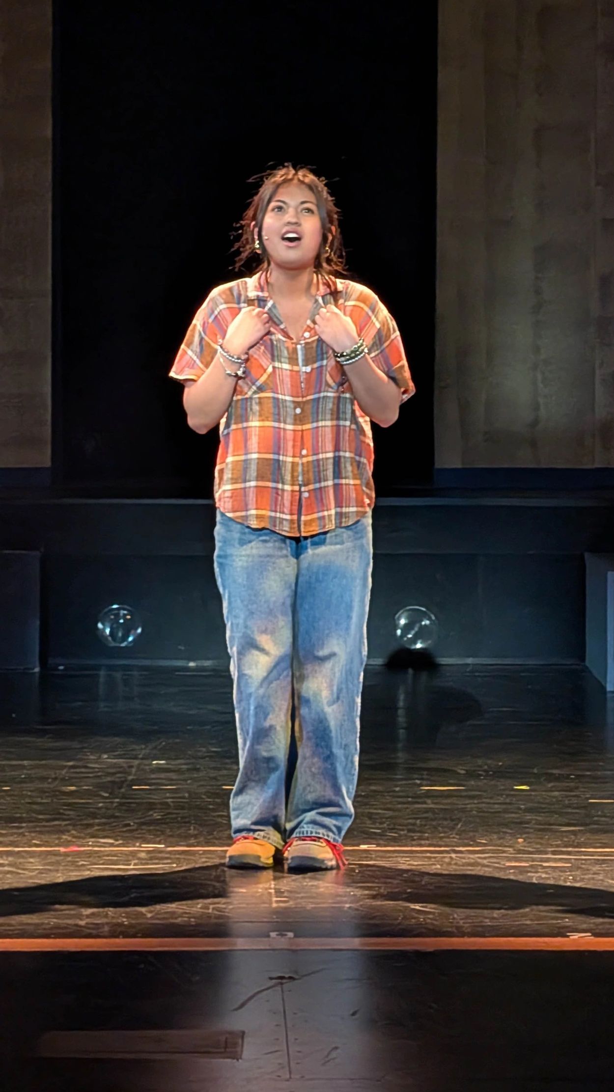 Woman confidently performing on stage in casual clothes.