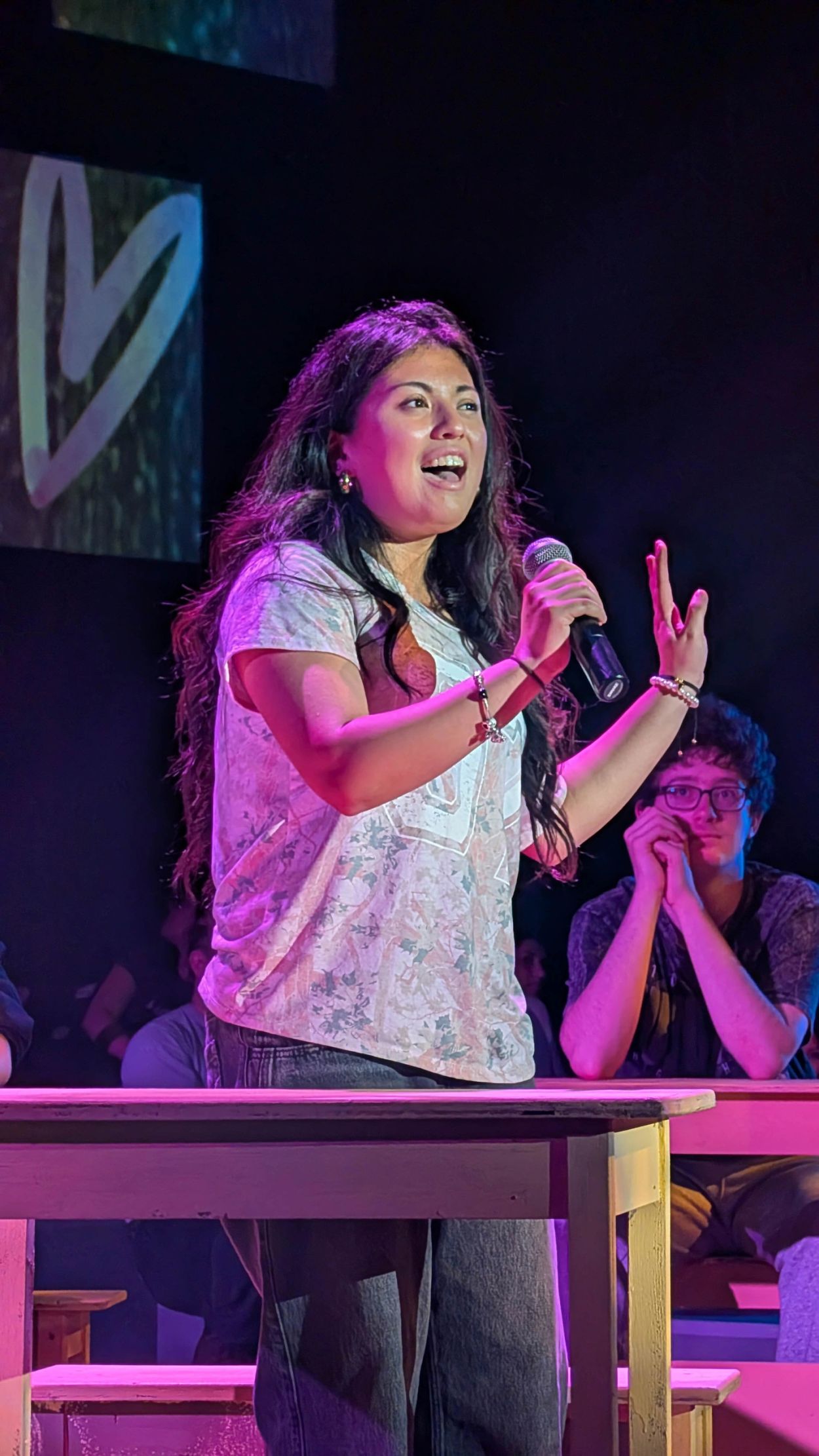 Woman passionately speaking with a microphone on stage.