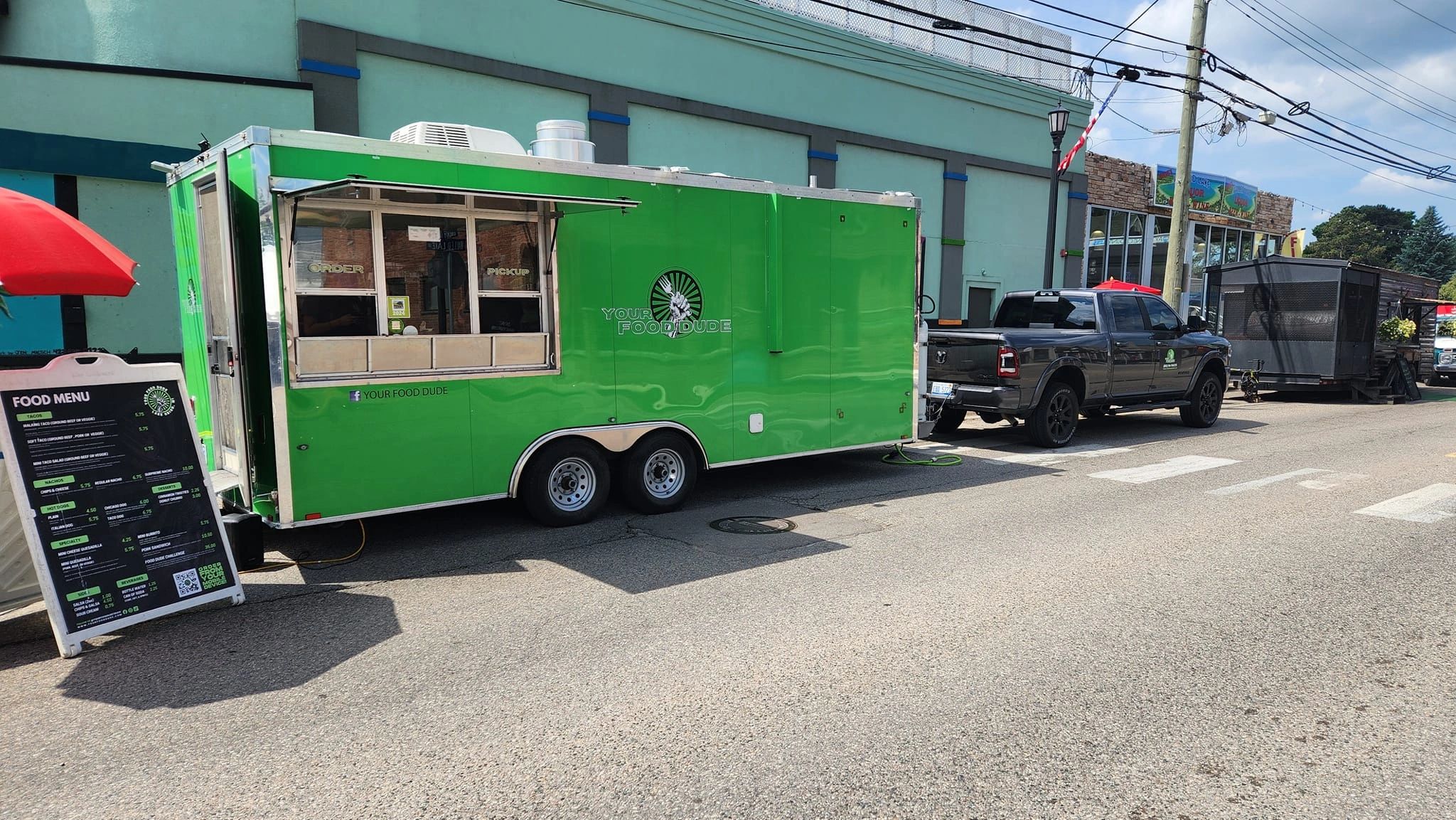 Green food truck named 'Your Food Dude' parked with menu board outside.