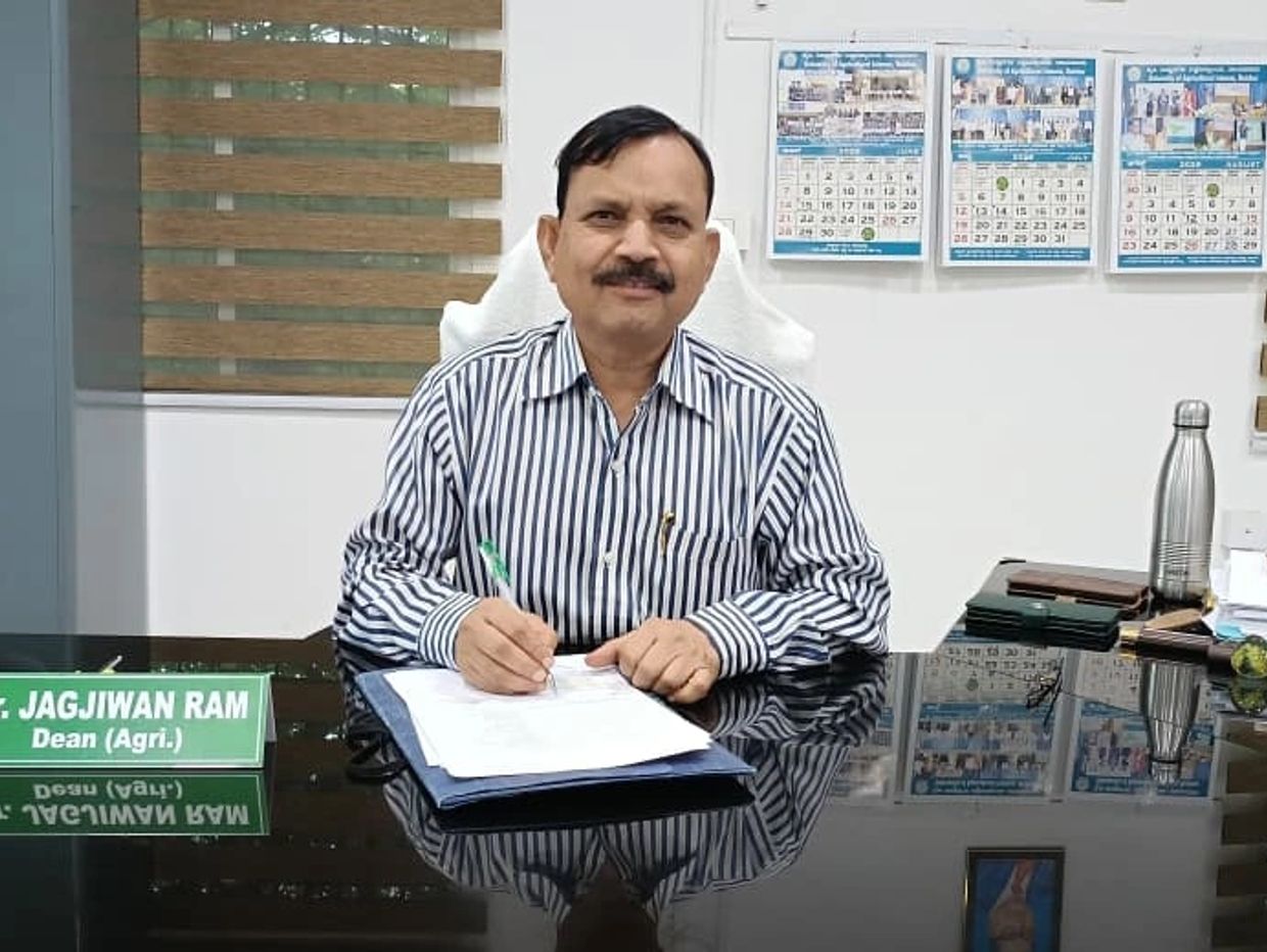 Man seated at desk signing documents with nameplate "Dr. Jagjiwan Ram".