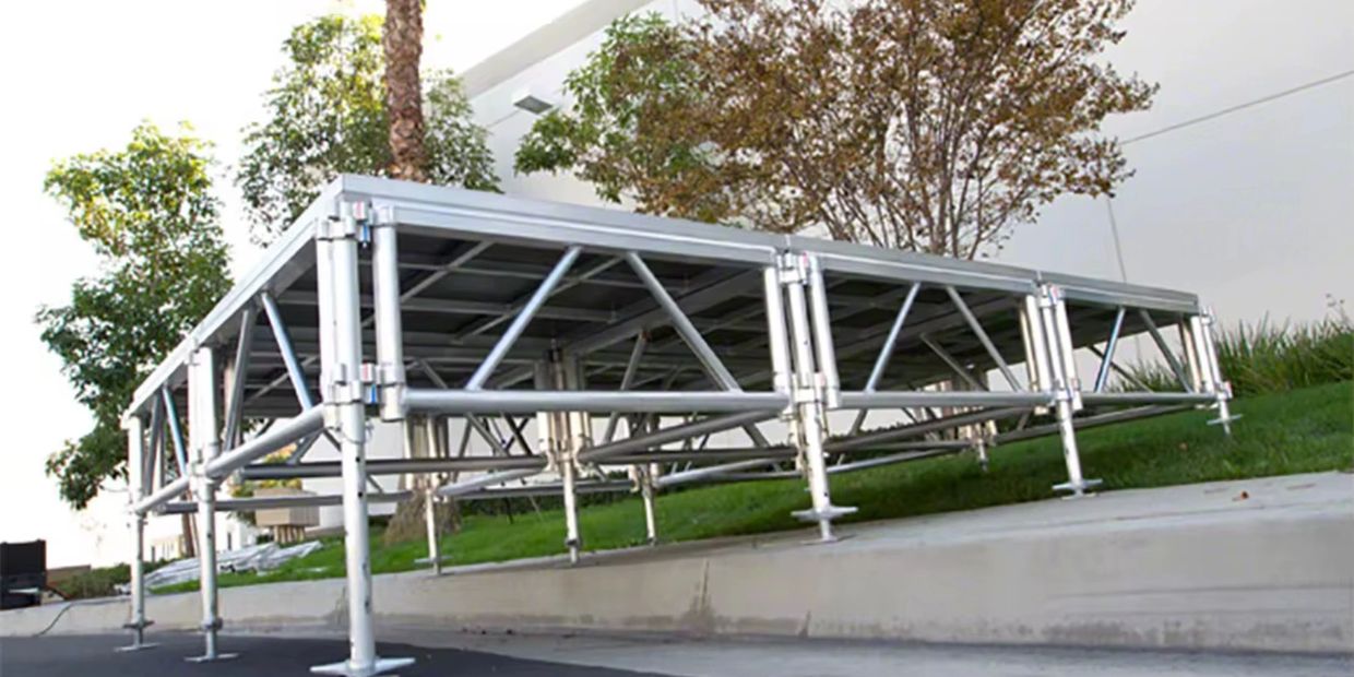 Adjustable metal stage platform set outdoors on uneven ground.