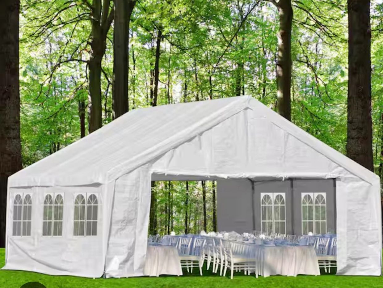 White outdoor party tent set up in a green forest area.