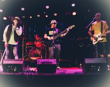 A band performs live on stage with colorful lighting.
