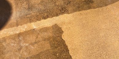 Sunlight casts shadows on a textured concrete surface.