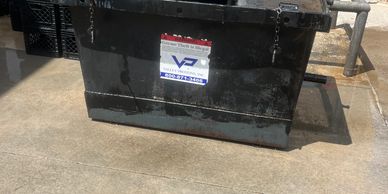Large black metal box with warning label on concrete floor.