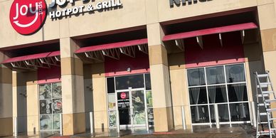 Exterior view of Joy Hotpot &amp; Grill restaurant with a ladder nearby.