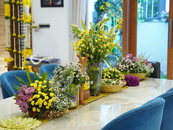 Colorful floral arrangements decorate a dining table with blue chairs.