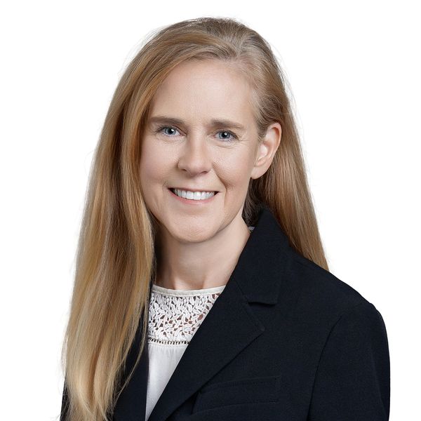 Professional headshot of Adrienne smiling in her black suit jacket.