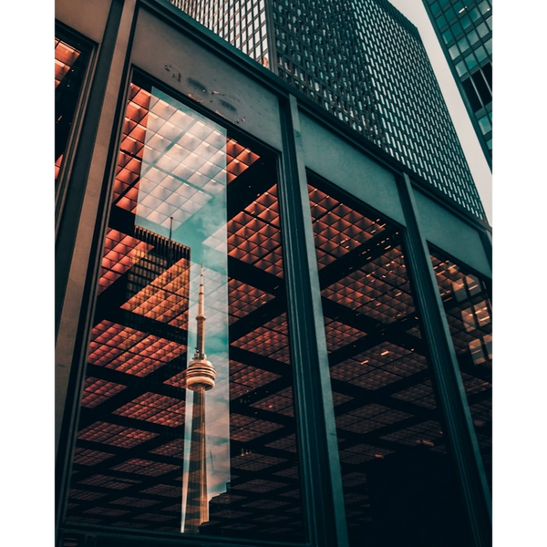 Reflection of a tall tower in the glass windows of a modern building.