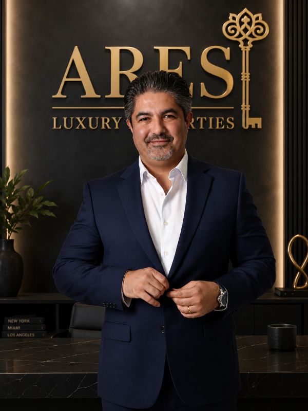 Man in a suit standing in front of ARES Luxury Properties sign.