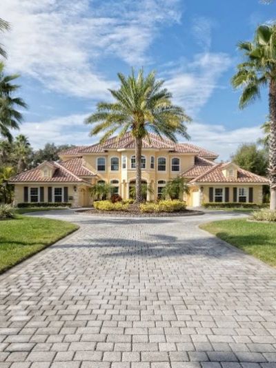 Large stucco home with pavers lining driveway
