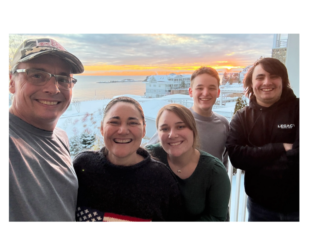 A happy family posing together during a snowy sunset by the sea.