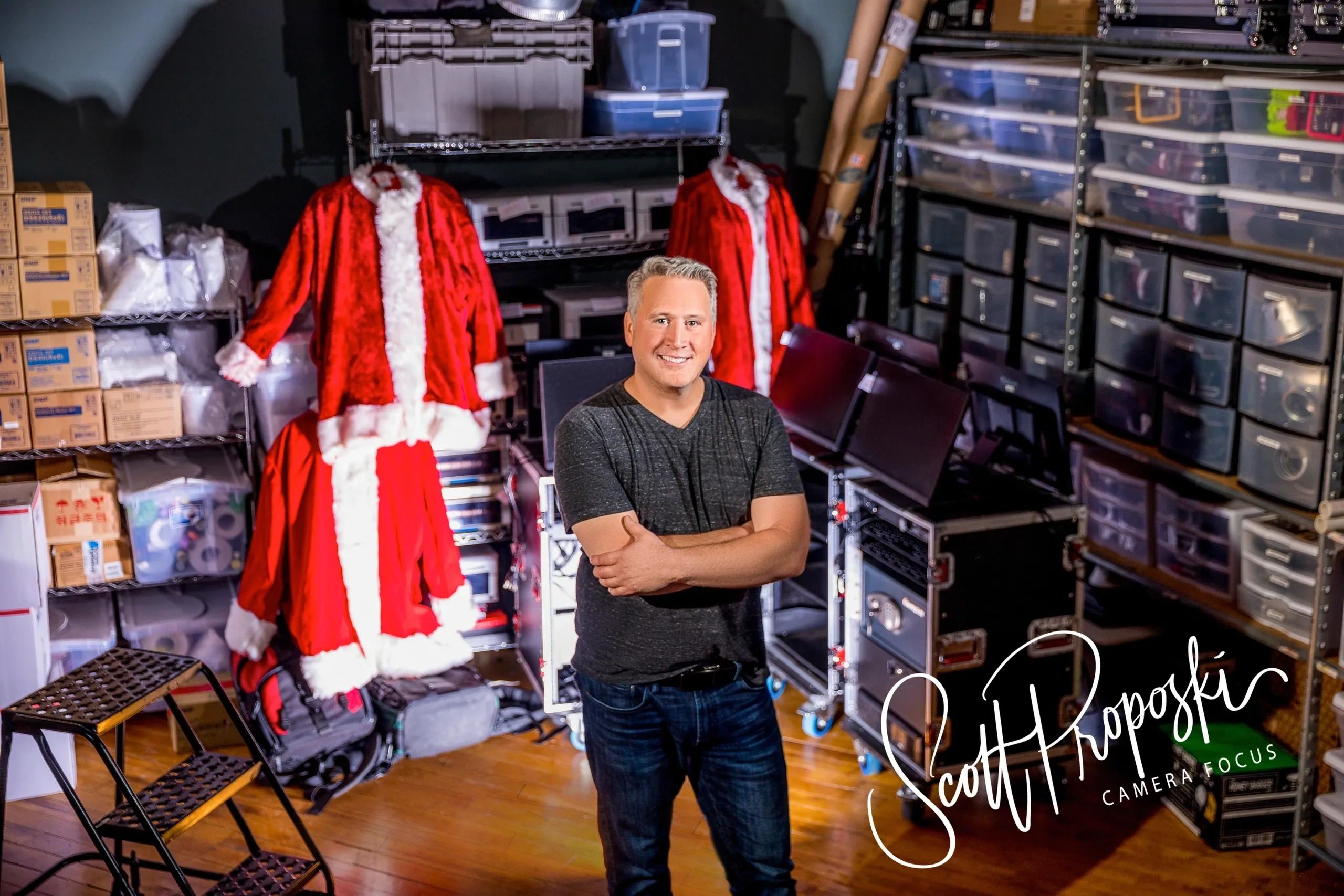 Man standing in a storage room filled with Santa suits and equipment.