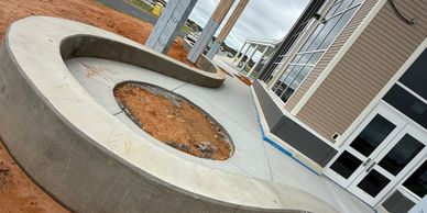 Curved concrete planter beside a modern building entrance under cloudy sky.