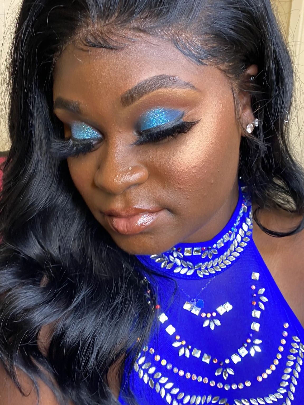 Woman with blue glitter eyeshadow and ornate blue dress.