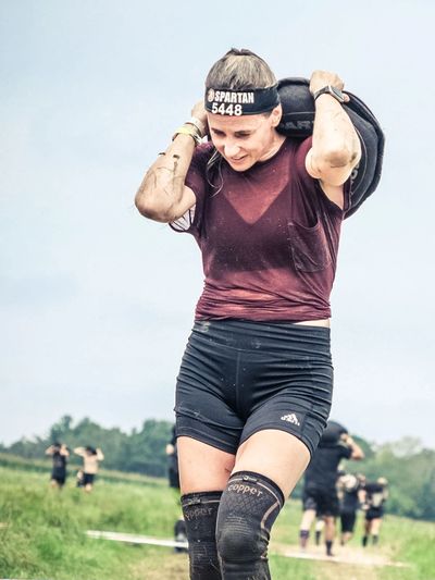 Woman carrying a heavy bag during a Spartan race event.