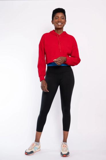 Smiling woman in red hoodie and black leggings.